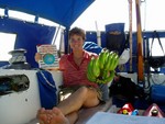 Looking back into the cockpit. That�s a hand of bananas HT has in her hand. The wooden thing is the tiller, used to steer the boat, better than a wheel. The propane tank is underneath it. 